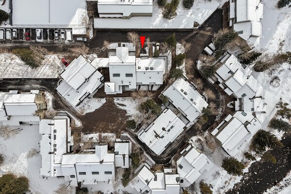 Un barrio residencial cubierto de nieve con varias casas independientes, cada una con un diseño de tejado diferente y ventanas dispuestas de distintas maneras.