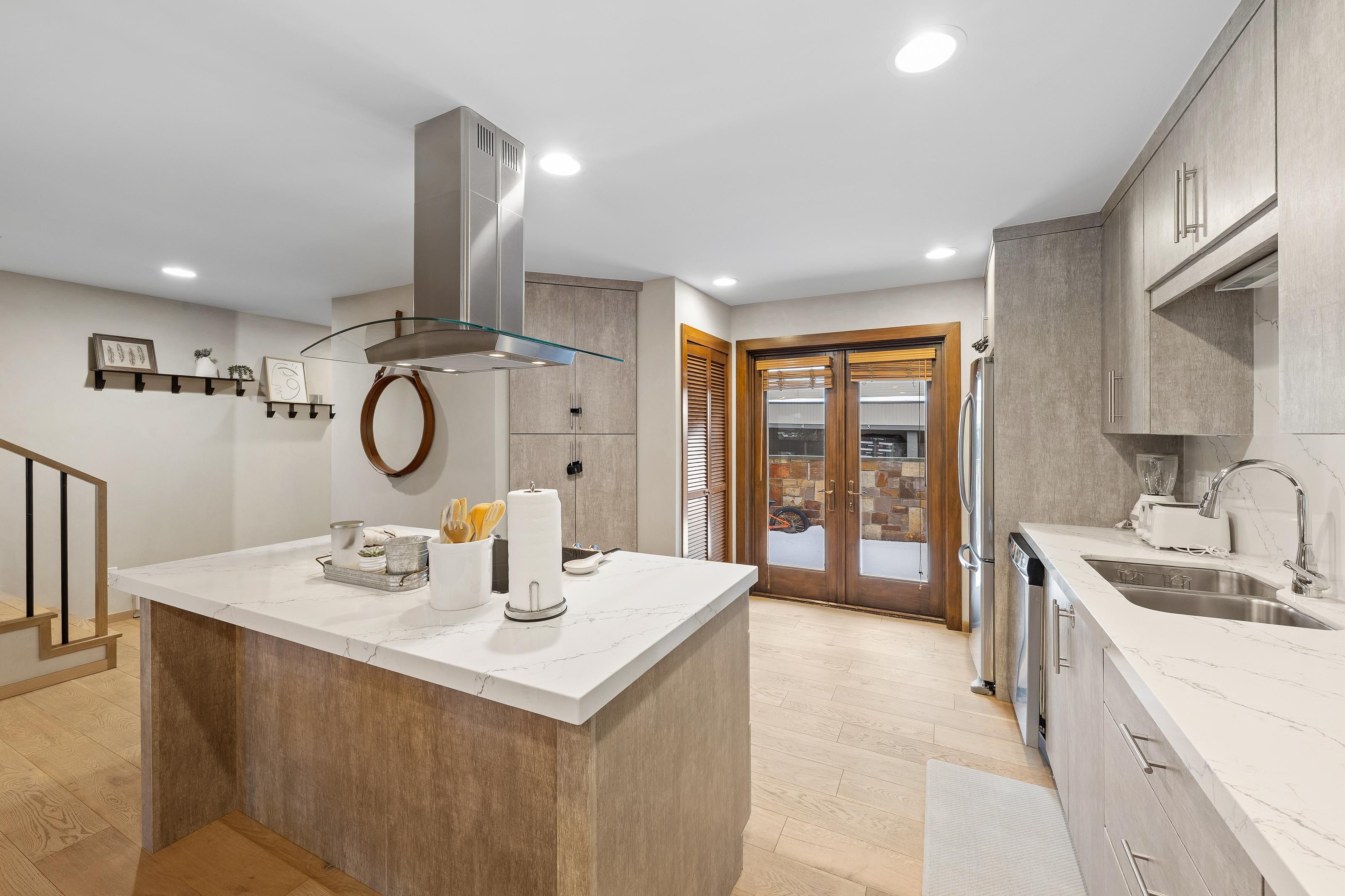 A modern kitchen with a central island, stainless steel appliances, and a view to the outside.