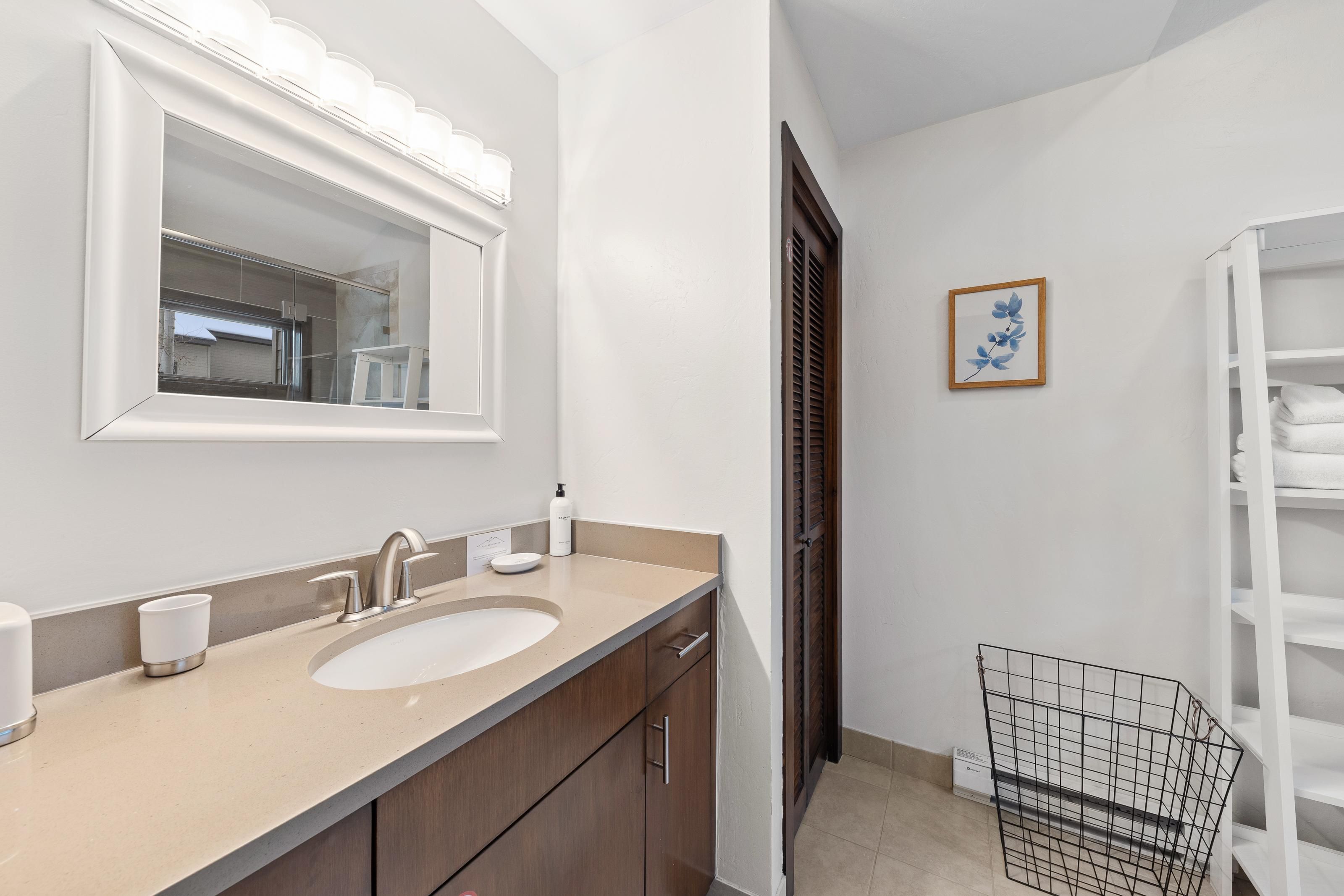 Un baño moderno con un espejo grande, dos lavamanos y un perchero para toallas.