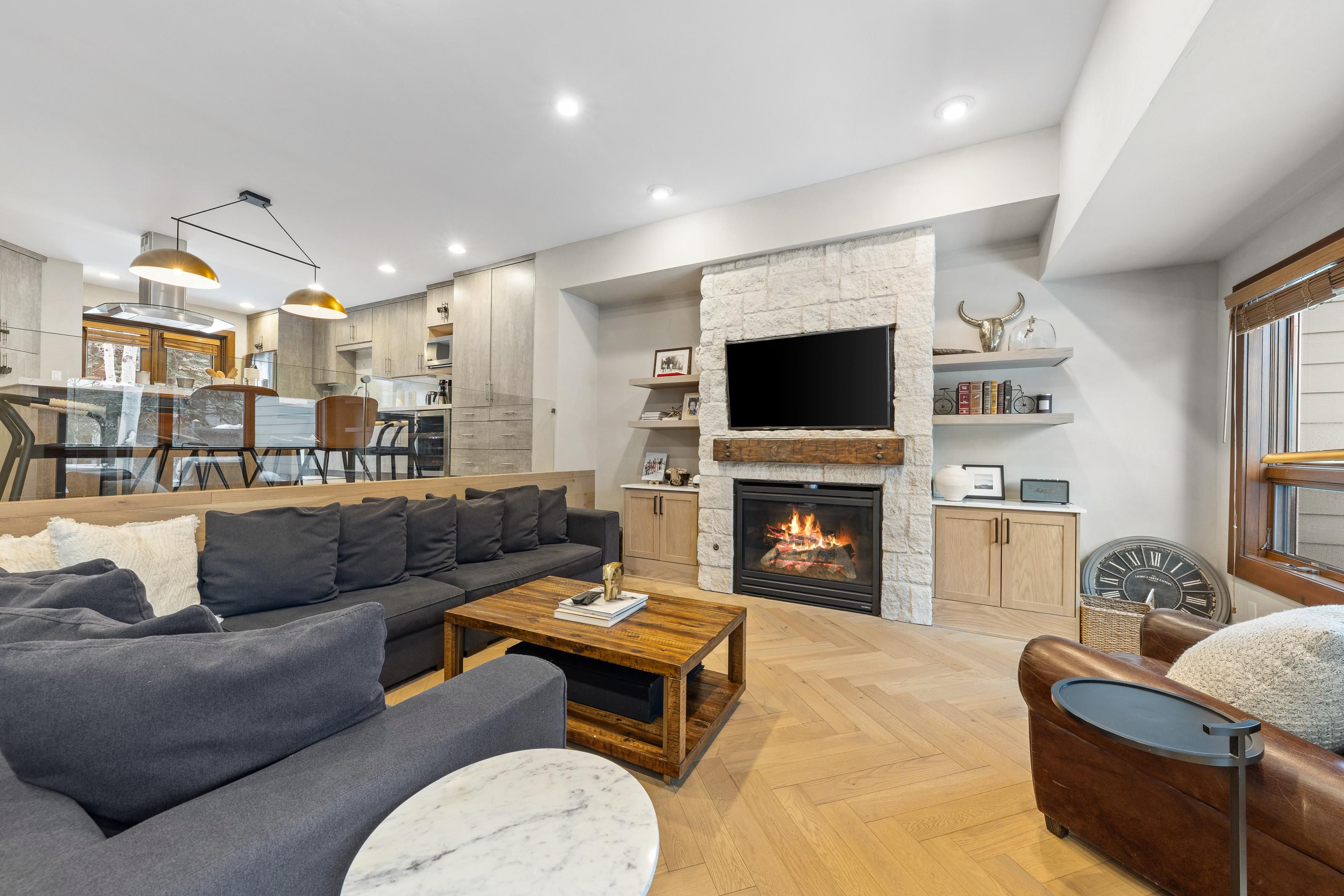A modern living room with a fireplace, a sofa, a coffee table, and a television.