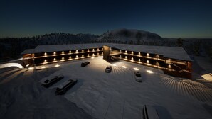 Een modern gebouw met meerdere parkeerplaatsen en een overdekt buitengebied, omgeven door besneeuwde heuvels.
