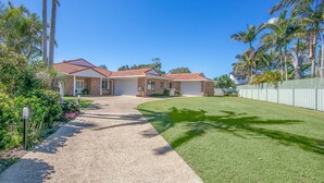 A two-story house with a brick exterior, a tiled roof, and a well-maintained lawn.