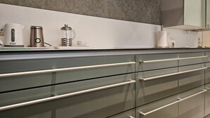 Une cuisine moderne dotée d’une hotte en acier inoxydable, d’une machine à café et d’un meuble avec des tiroirs et des portes en verre.