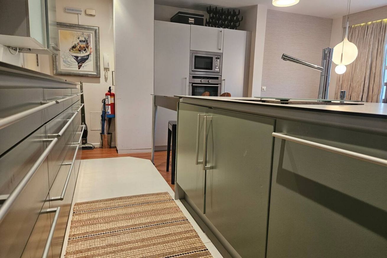 Una cocina moderna con electrodomésticos de acero inoxidable, microondas integrado y refrigerador de acero inoxidable.