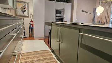 Una cocina moderna con electrodomésticos de acero inoxidable, microondas integrado y refrigerador de acero inoxidable.