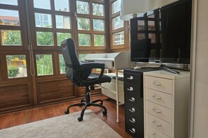 Una habitación con escritorio, silla, televisión y archivador.