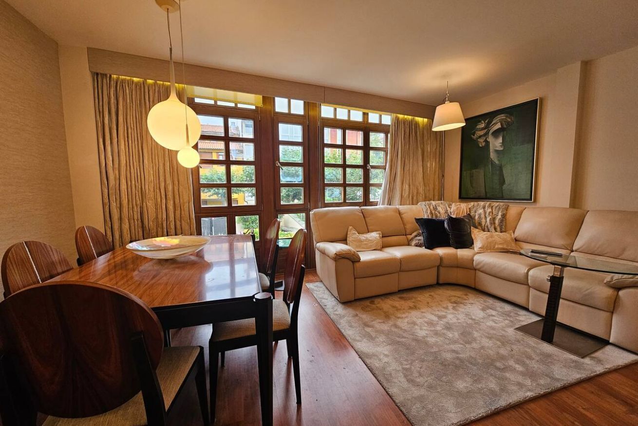 Een moderne woonkamer met een houten eettafel, een beige bank en een glazen salontafel.