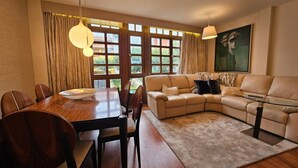 Un salon moderne avec une table à manger en bois, un canapé beige et une table basse en verre.