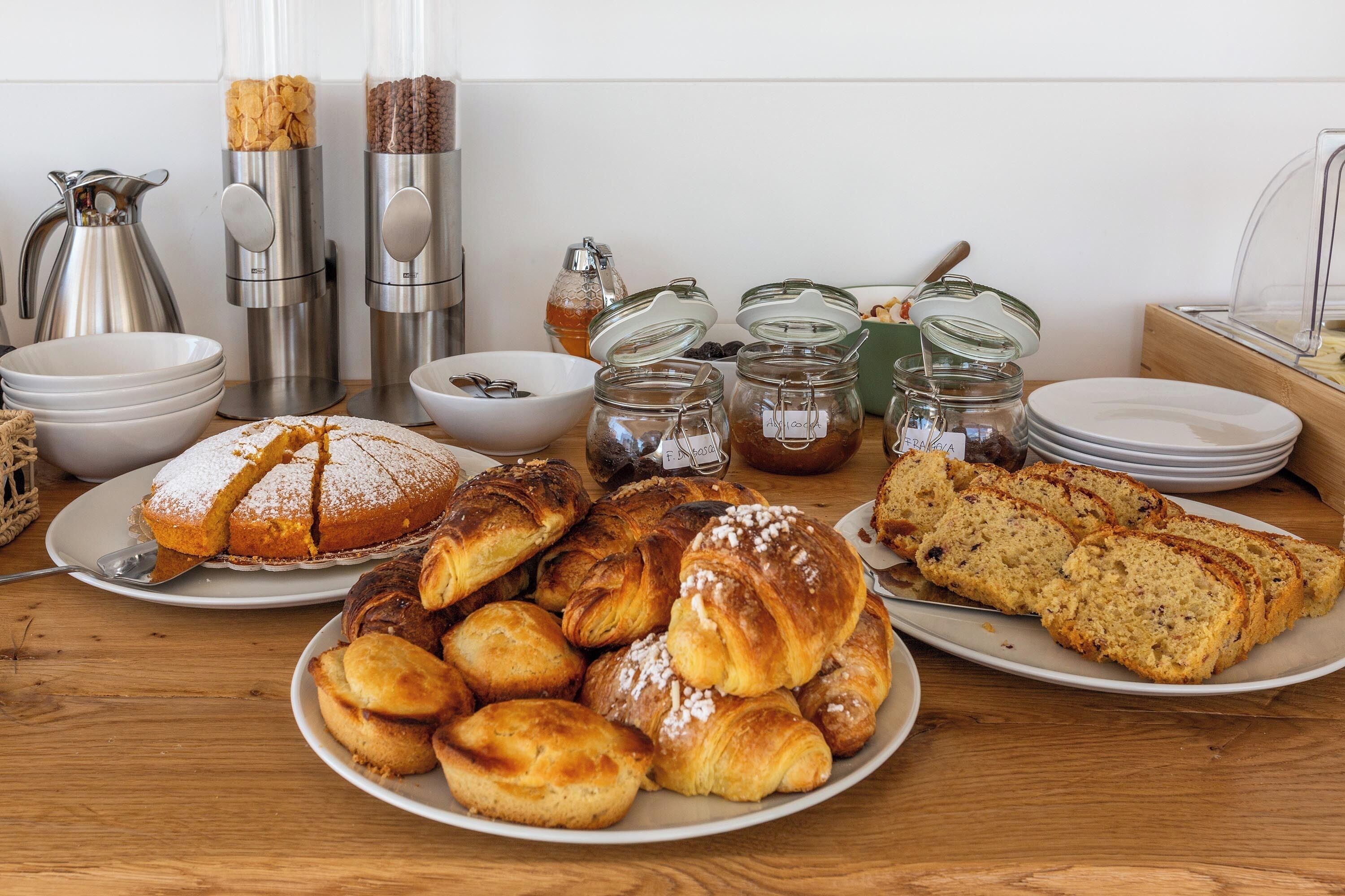 Un buffet de petit-déjeuner proposant un assortiment de viennoiseries, de pains et de condiments.