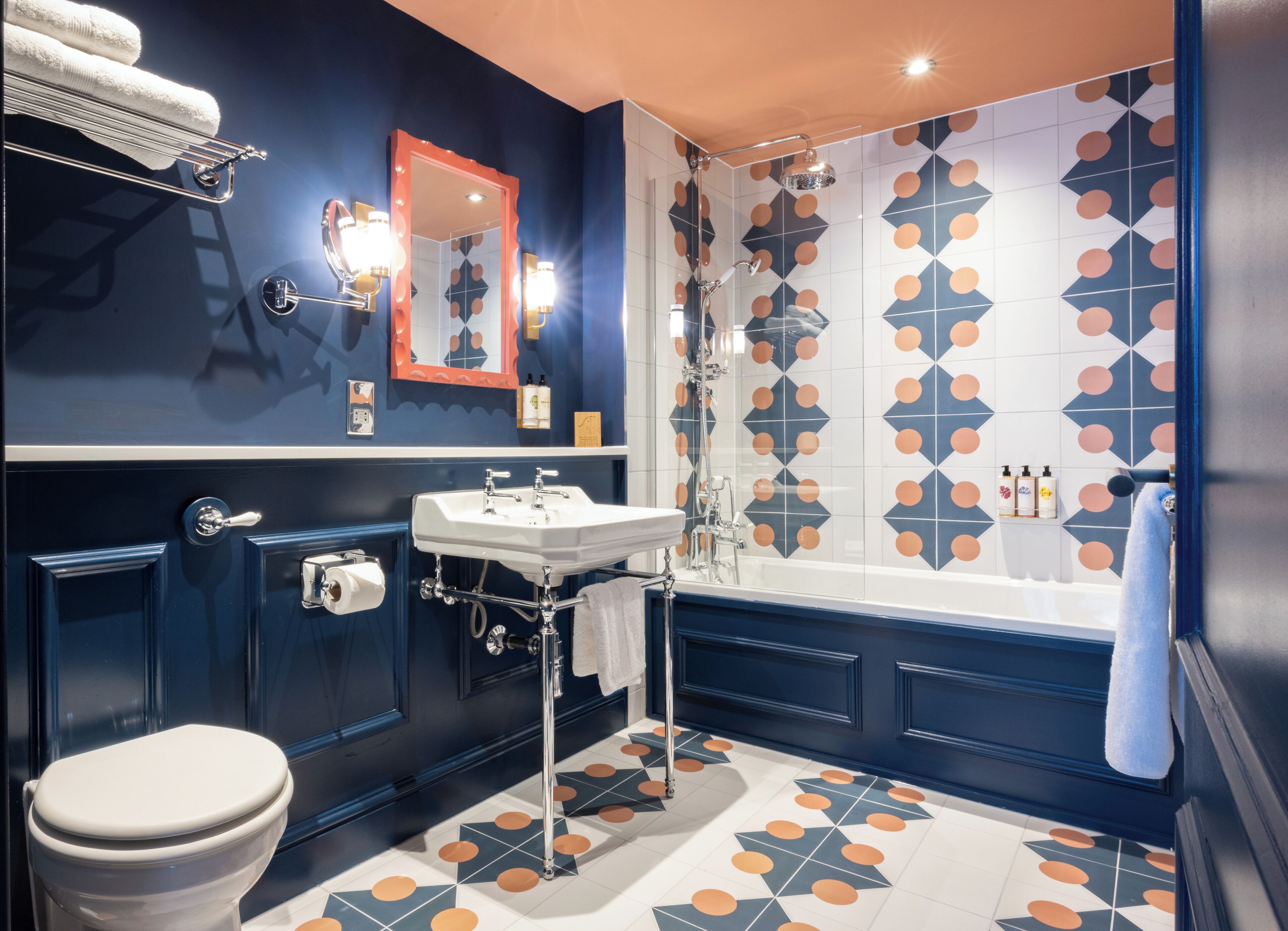 A bathroom with a white sink, a toilet, a shower, and a mirror with lights.