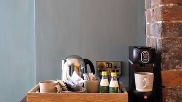 A wooden tray with coffee cups, a coffee maker, and a framed picture on a wall.