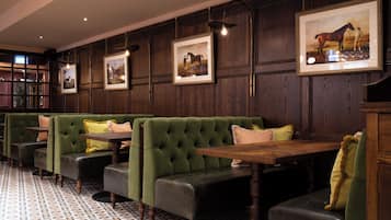 A restaurant with green upholstered booths, wooden tables, and framed pictures on the walls.