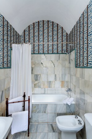 A bathroom with a bathtub, a bidet, and a shower curtain. - Hospedium Hotel Cortijo Torre De La Reina (Guillena)