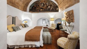 Un dormitorio amplio con una cama grande, una silla, un escritorio y un mural en la pared.