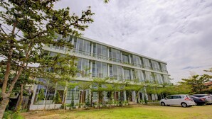 A modern building with a flat roof, large windows, and a covered outdoor area with potted plants. - Capital O 3840 Java Hotel & Resto (Cilacap)