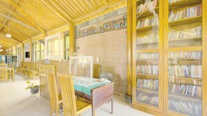 A library with wooden bookshelves, tables, and chairs. - Capital O 3840 Java Hotel & Resto (Cilacap)