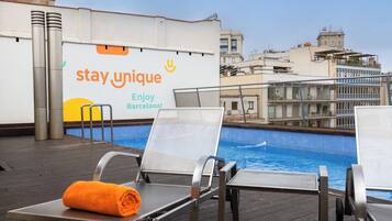 Un área de piscina en la azotea con sillas de descanso, una toalla y un cartel que dice 'stay unique'.