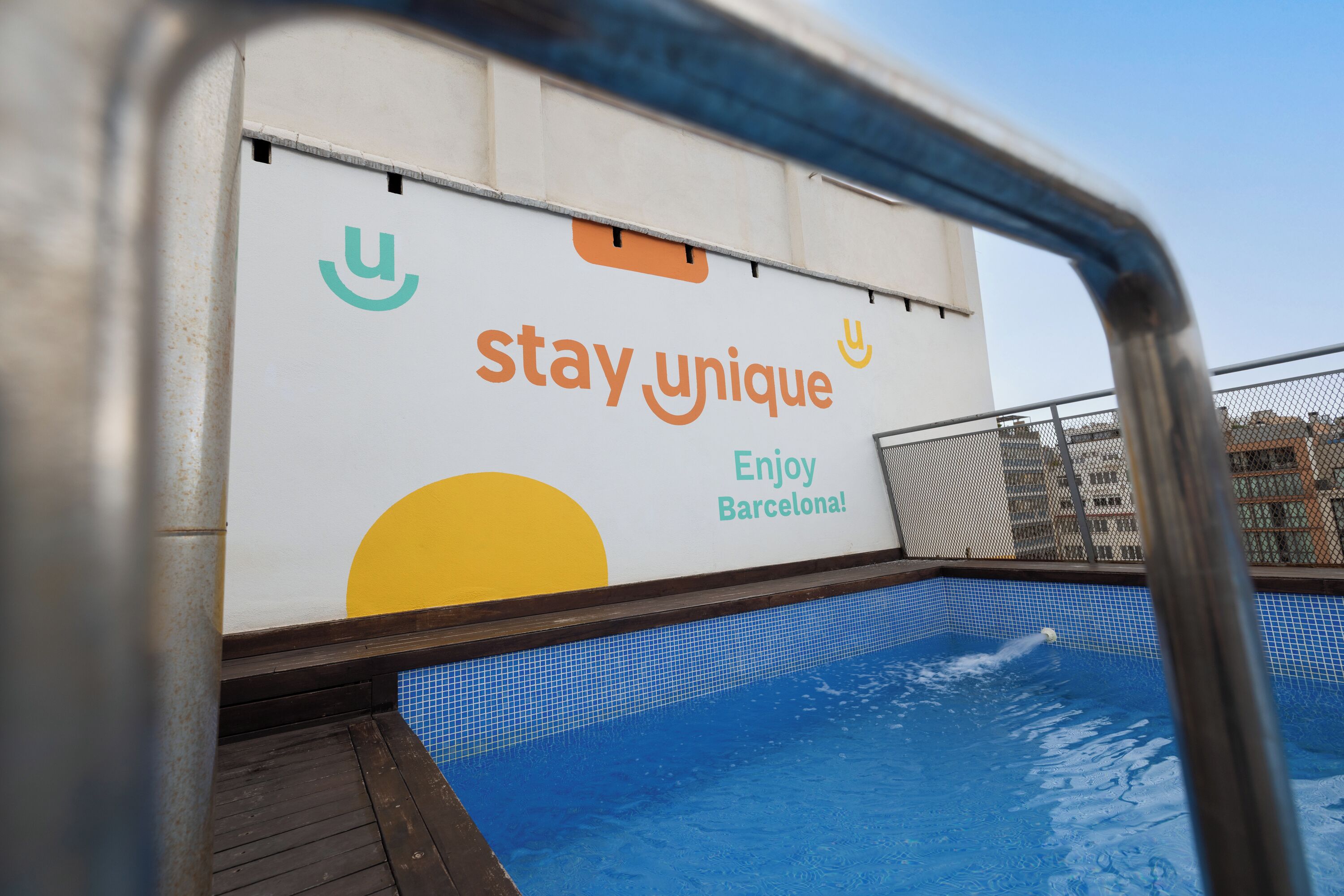 A swimming pool with a sign that reads 'stay_unique Enjoy Barcelona!'