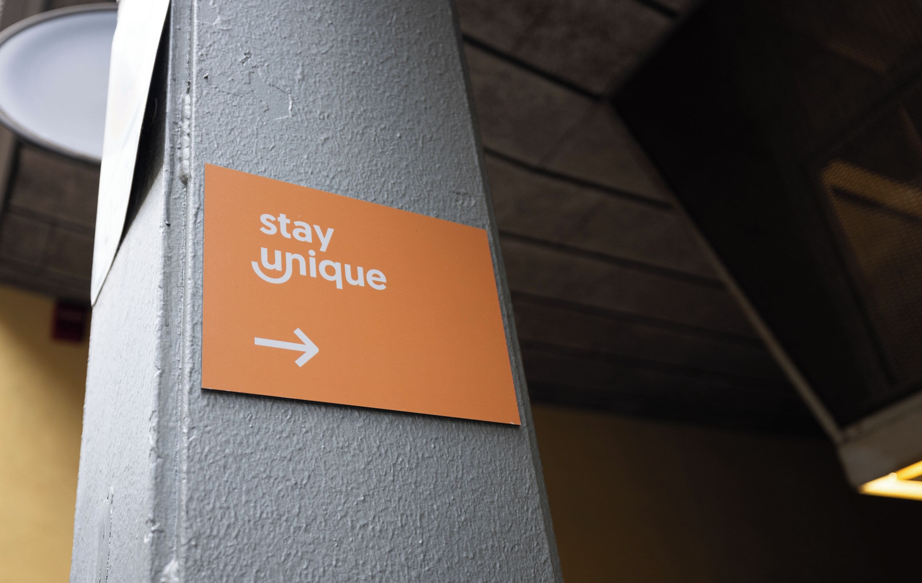 A sign on a pillar with the text 'stay unique' and an arrow pointing to the right.