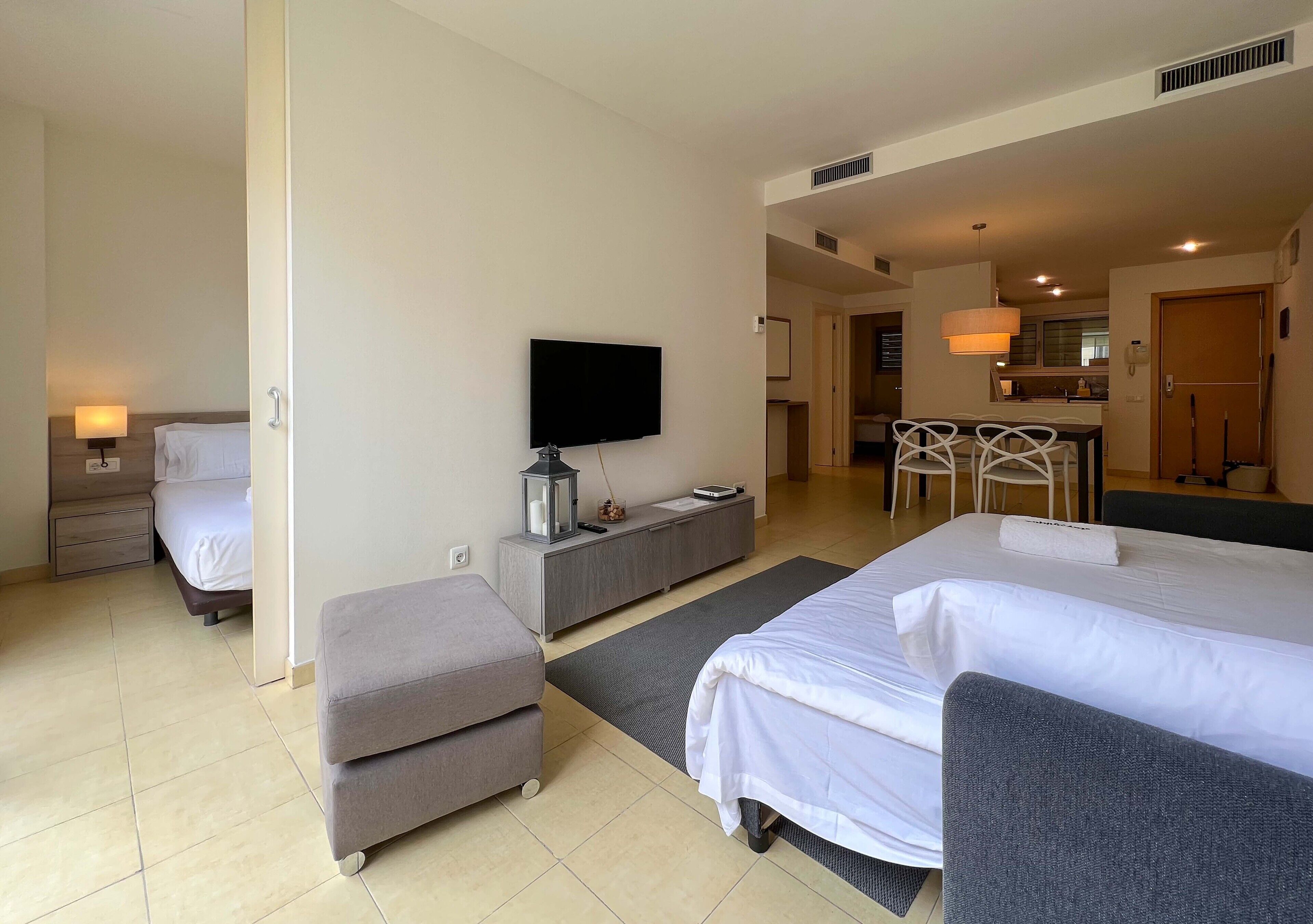 Une chambre d’hôtel avec deux lits, une télévision, un bureau et une kitchenette.