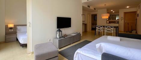 Une chambre d’hôtel avec deux lits, une télévision, un bureau et une kitchenette.