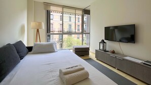 Een moderne hotelkamer met een groot bed, een televisie, een bureau en een raam met uitzicht op de stad.