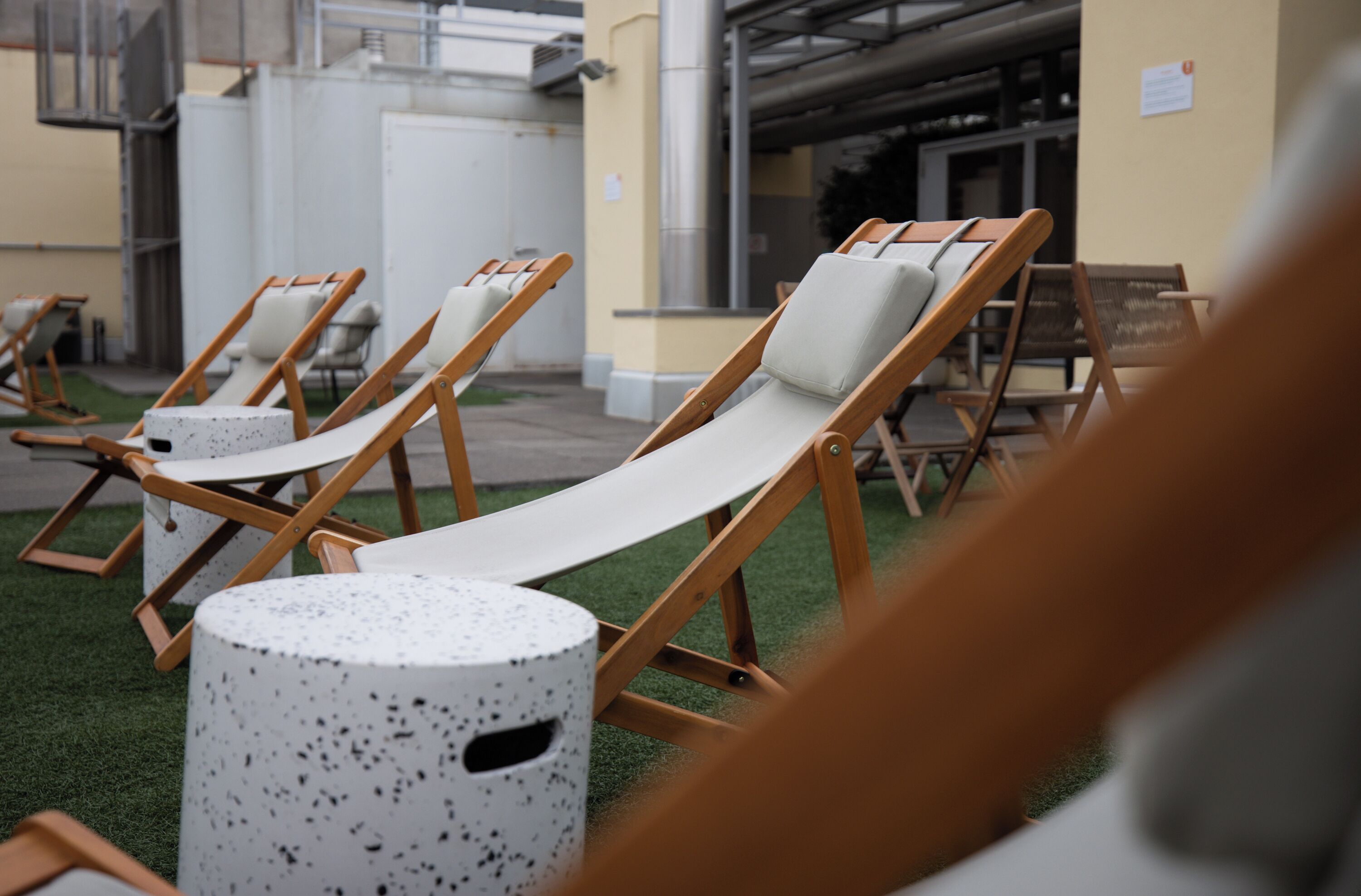 Lounge chairs arranged on artificial grass with a building in the background.