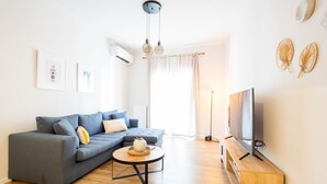 A modern living room with a grey sofa, a round coffee table, a flat-screen TV, and a wooden cabinet. - Urban Comfort 2 Bdrm Next to Metro (Athens)