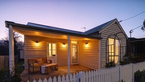 A single-story house with a covered porch, a white picket fence, and a bench. - Nelly's Cottage Braidwood - cosy cottage in a picture perfect country setting (Braidwood)