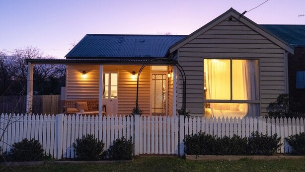 A single-story house with a porch, a picket fence, and a small garden. - Nelly's Cottage Braidwood - cosy cottage in a picture perfect country setting (Braidwood)