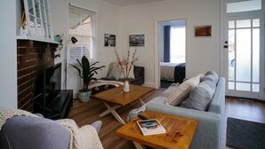 A living room with a fireplace, a sofa, a coffee table, and a television. - Nelly's Cottage Braidwood - cosy cottage in a picture perfect country setting (Braidwood)