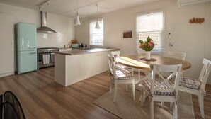A modern kitchen with a central island, white cabinetry, and a teal refrigerator. - Nelly's Cottage Braidwood - cosy cottage in a picture perfect country setting (Braidwood)