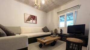 A modern living room with a sofa, a coffee table, a television, and a window. - Sias Cozy House (Sithonia)