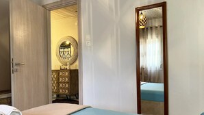 A hotel room with a bed, a wooden wardrobe, a mirror, and a circular wall decoration. - Sias Cozy House (Sithonia)