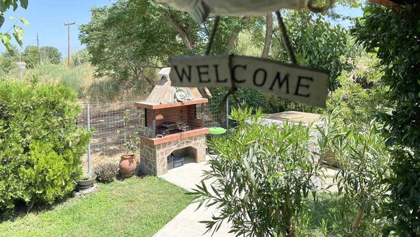 A 'WELCOME' sign above a barbecue area surrounded by greenery. - Sias Cozy House (Sithonia)