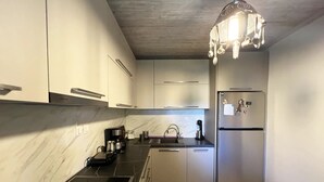 A modern kitchen with a black countertop, stainless steel appliances, and a marble backsplash. - Sias Cozy House (Sithonia)
