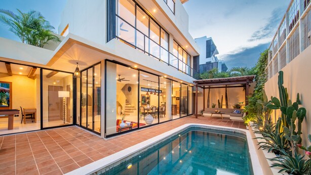 Een modern huis met zwembad, grote glasramen en een terras.