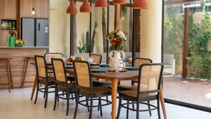 Een eetgedeelte met een houten tafel, rieten stoelen en een bloevas.