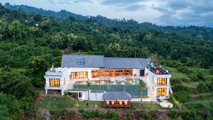 A modern house with a large swimming pool, surrounded by lush greenery and hills. - Infinity Pool | Private Wellness Space | Sea Views (Lovina)