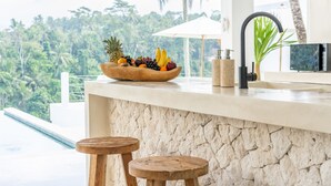 Una encimera de cocina con un frutero, un lavabo y una pared de piedra.