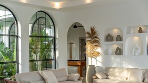 Una sala de estar moderna con un sofá, sillones, una mesa de centro y un ventanal con vistas a zonas verdes.