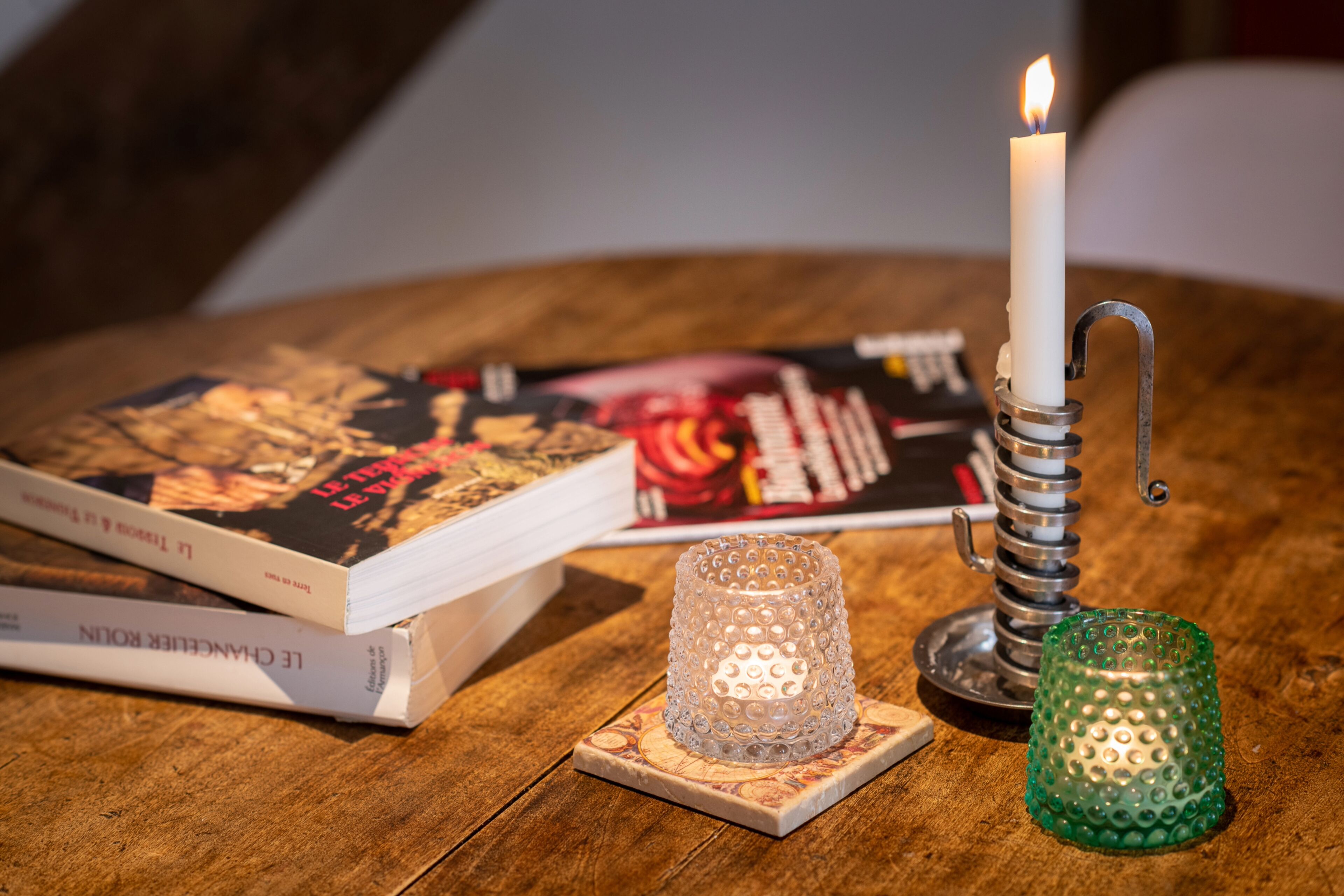 Une table en bois avec une bougie allumée, un livre et un chandelier.