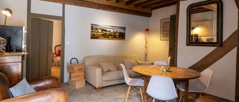 A cozy room with a wooden ceiling, a dining table with chairs, a sofa, and a large mirror on the wall.