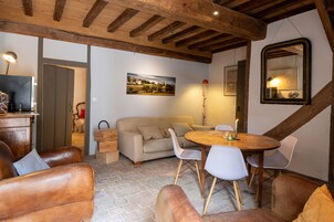 Una habitación acogedora con techo de madera, una mesa de comedor con sillas, un sofá y un espejo grande en la pared.