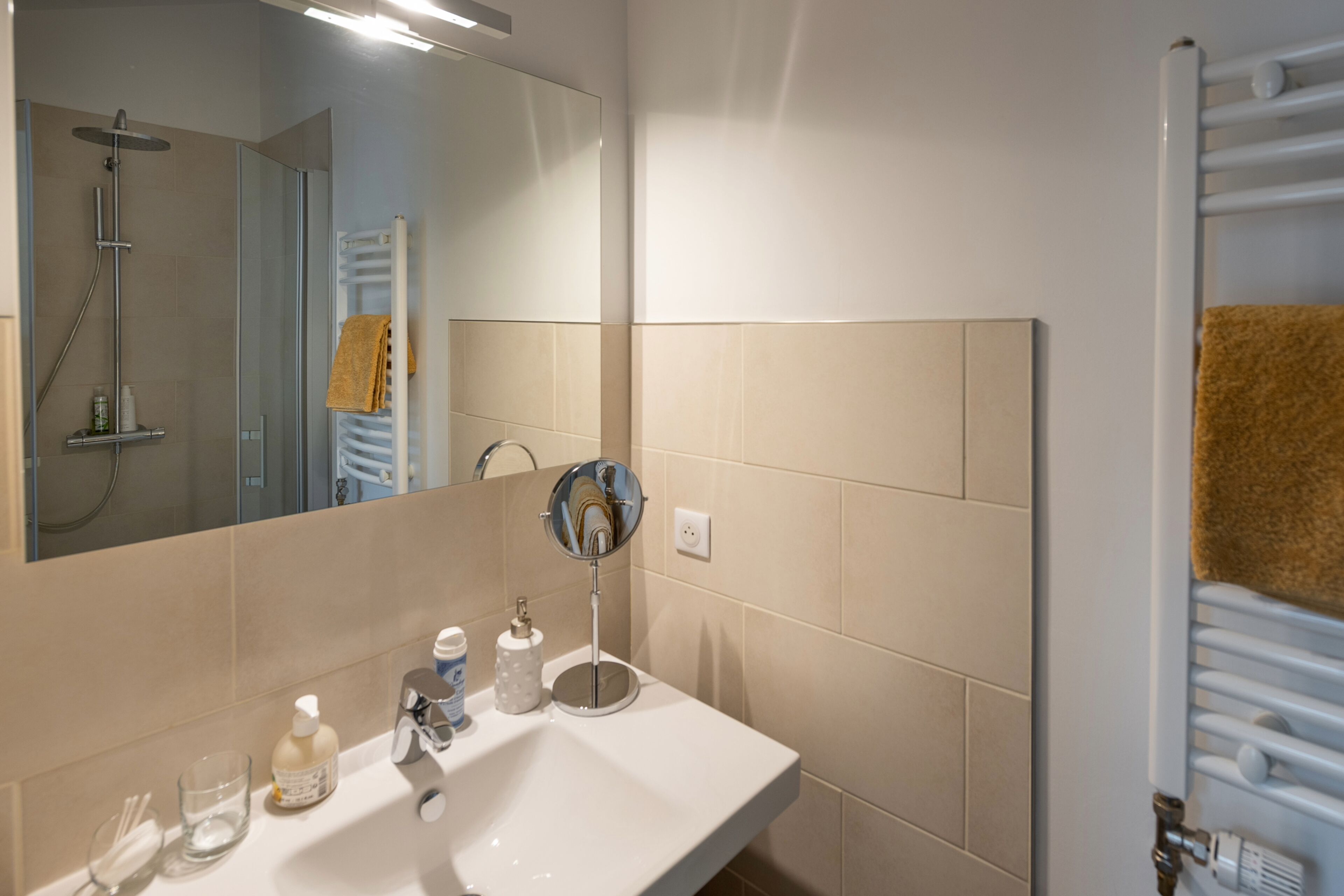 A bathroom with a sink, mirror, and towel rack.