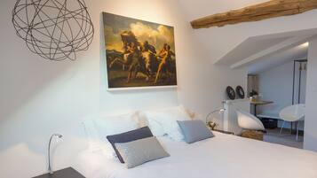 Ein modernes Schlafzimmer mit einem großen Bett, einem Schreibtisch und einem Stuhl. Ein Gemälde hängt an der Wand, und es gibt eine einzigartige, kugelförmige Leuchte.