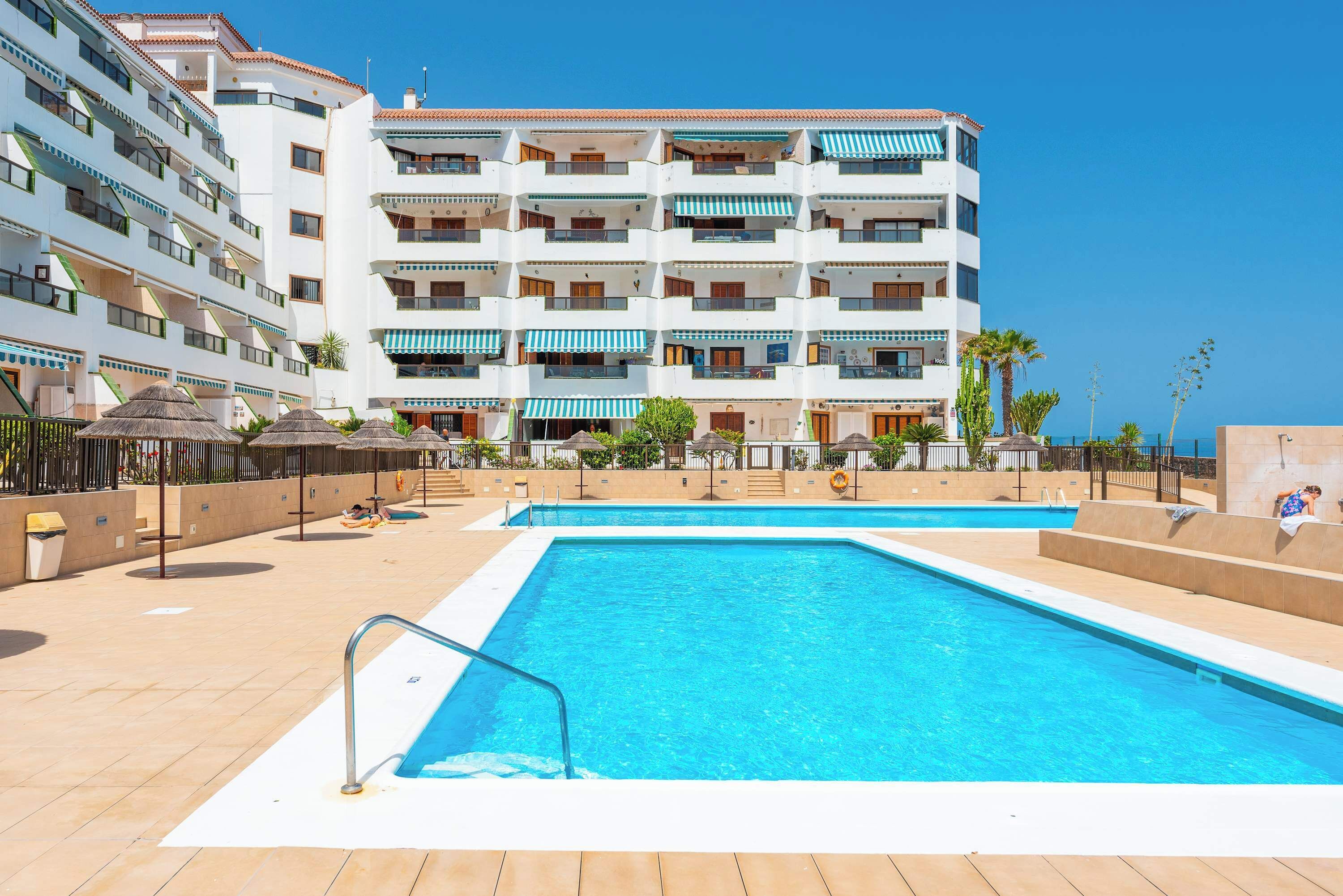 Un hôtel doté d’une piscine, de nombreux balcons et offrant une vue sur un ciel d’un bleu éclatant.