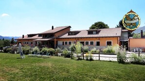 A two-story house with a tiled roof, a fenced yard, and a mountain backdrop. - Hotel Cocoon (Pescasseroli)
