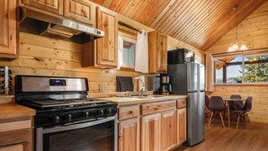 A wooden cabin kitchen with a stove, oven, sink, and refrigerator. - Adventure Log Cabin with Expansive Views, Discovery Ski Hill nearby, walk to downtown. Perfect for couples and small families! (Philipsburg)
