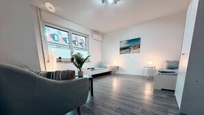 A modern living room with a sofa, a dining area with a table and chairs, and a kitchen in the background. - StadtHOUSE Bentheim – Viel Platz für Gruppen (Bad Bentheim)